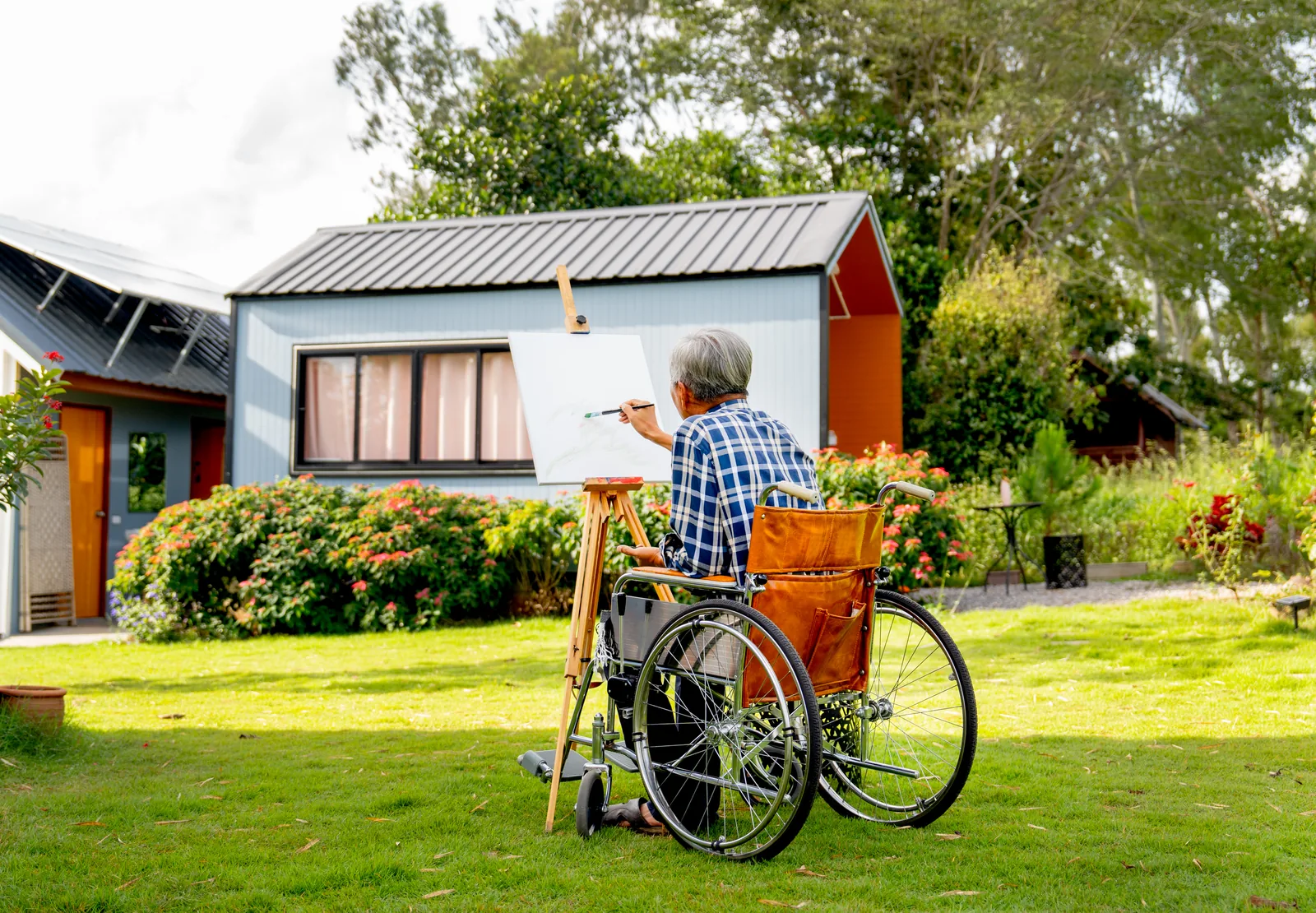 Oudere man schilderd in tuin van mantelzorgwoning