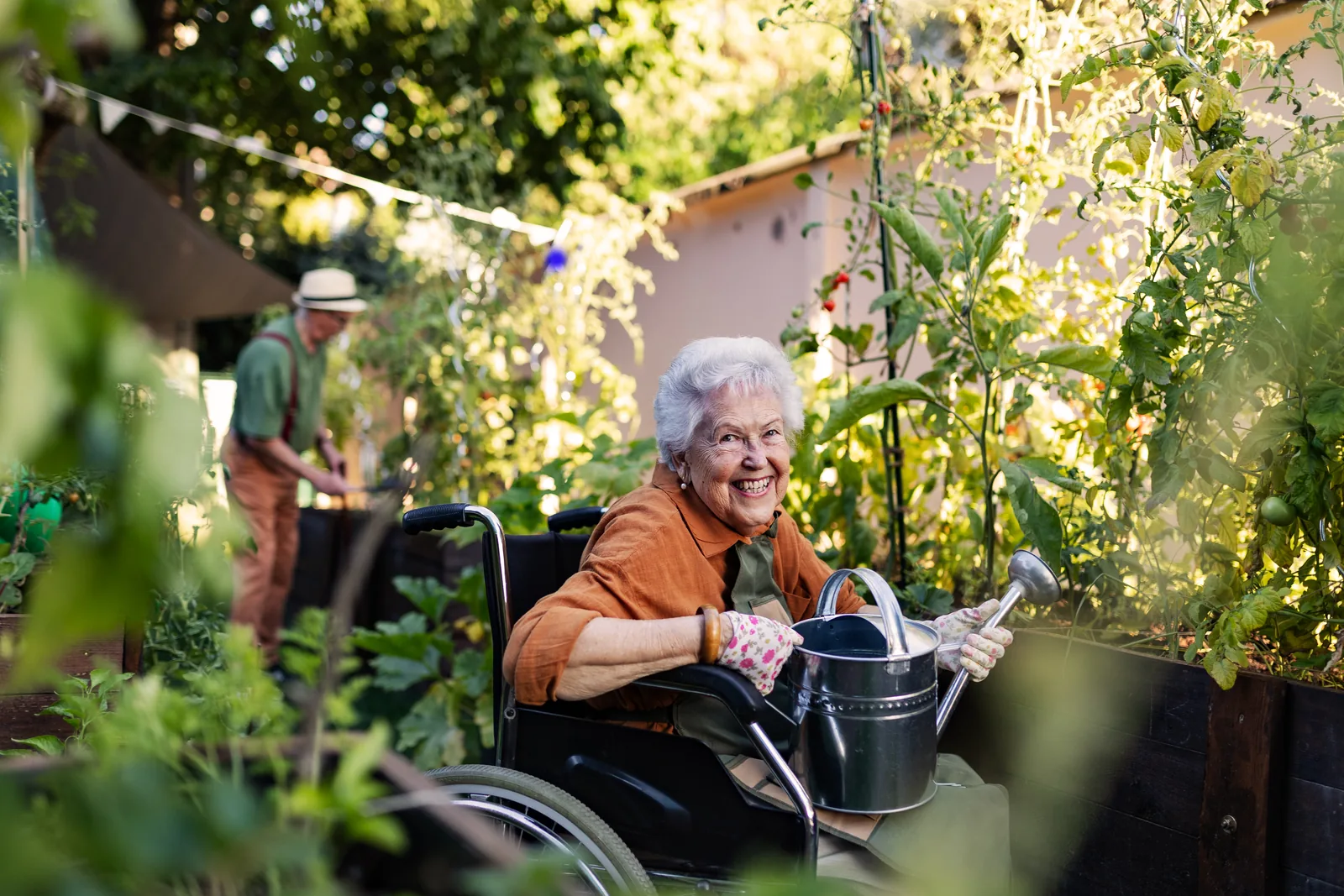 Oudere vrouw in een rolstoel verzorgt haar planten