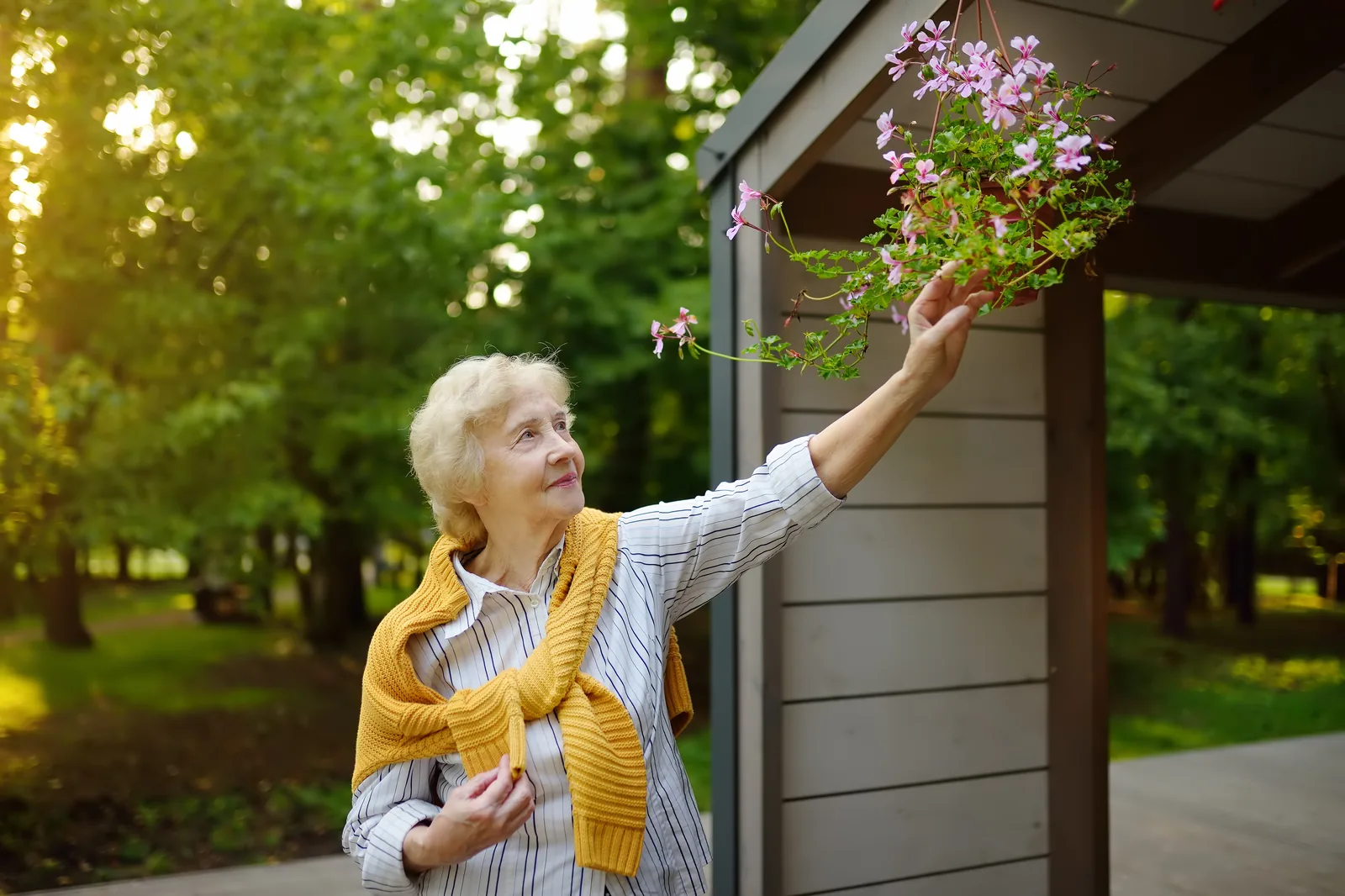 Oudere vrouw geniet van de bloemen in haar tuin