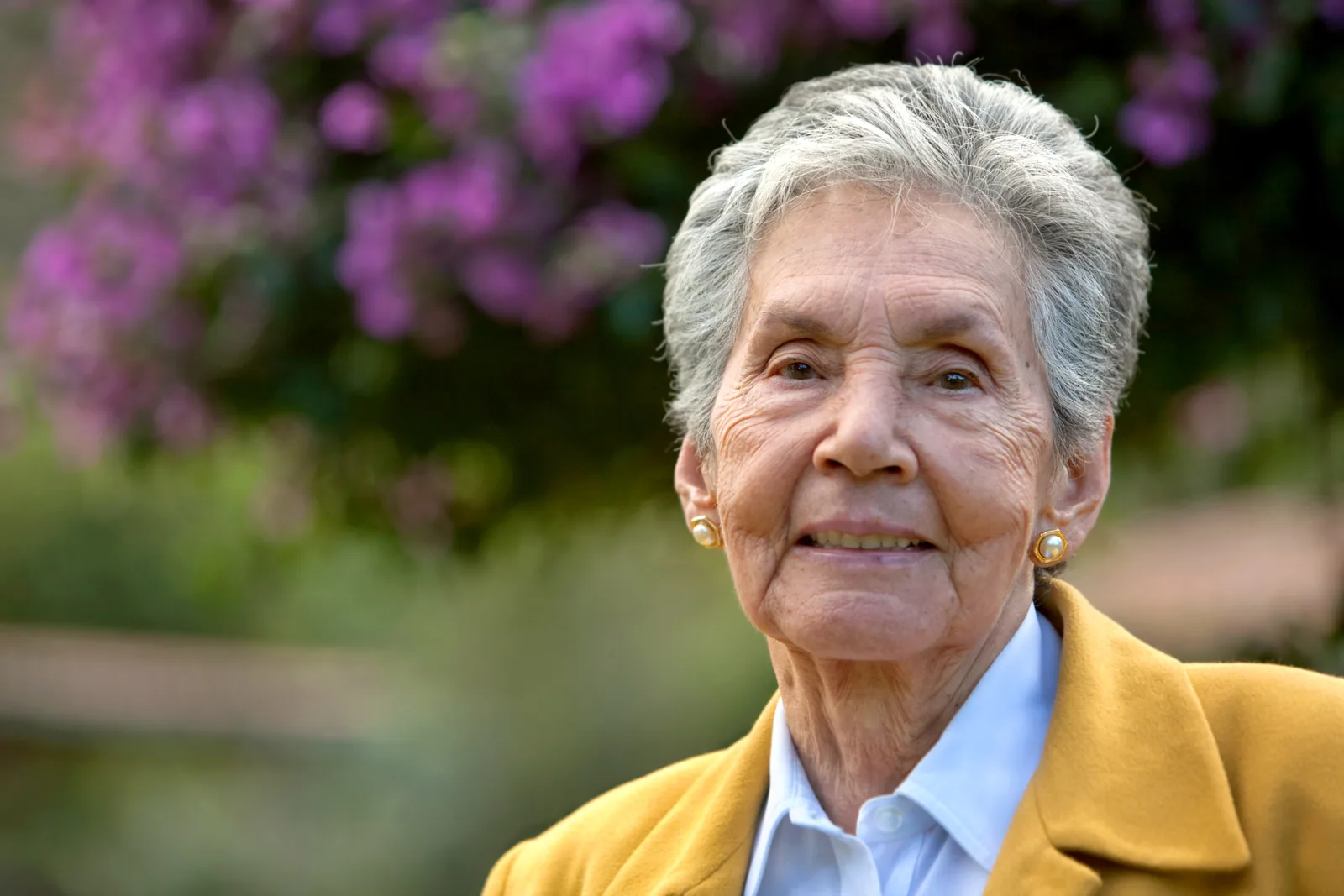 Lachende oudere vrouw tegen een bloemenachtergrond
