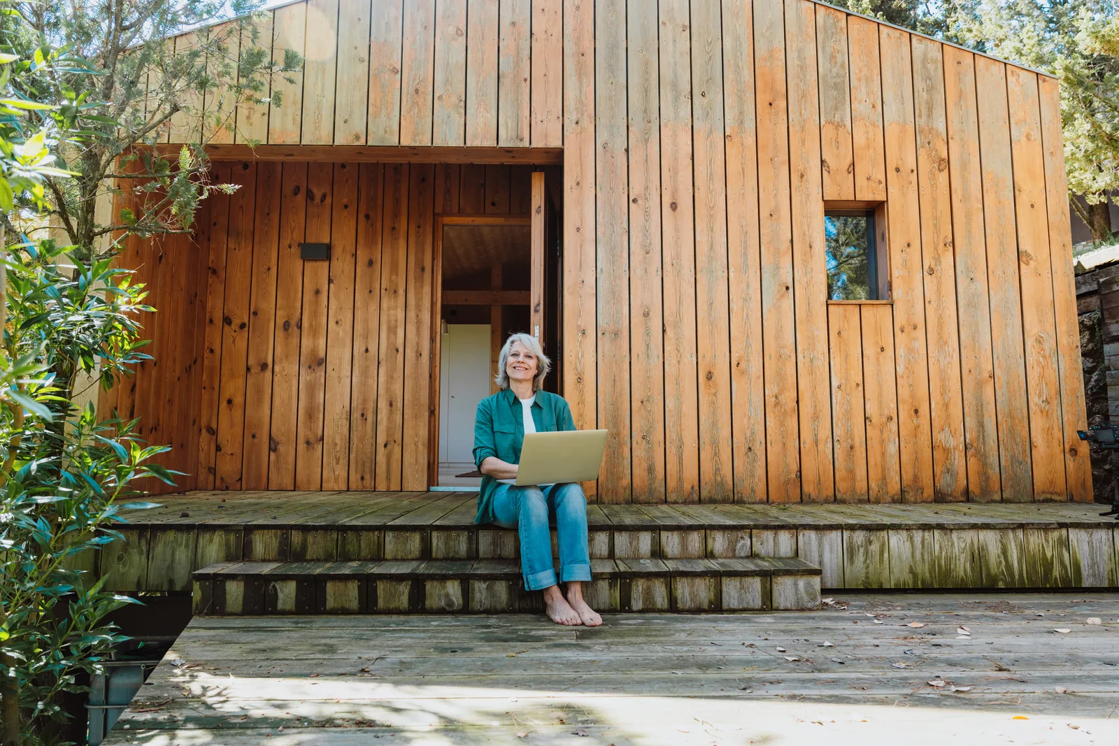 Vrouw werkt op de laptop bij een houten woning